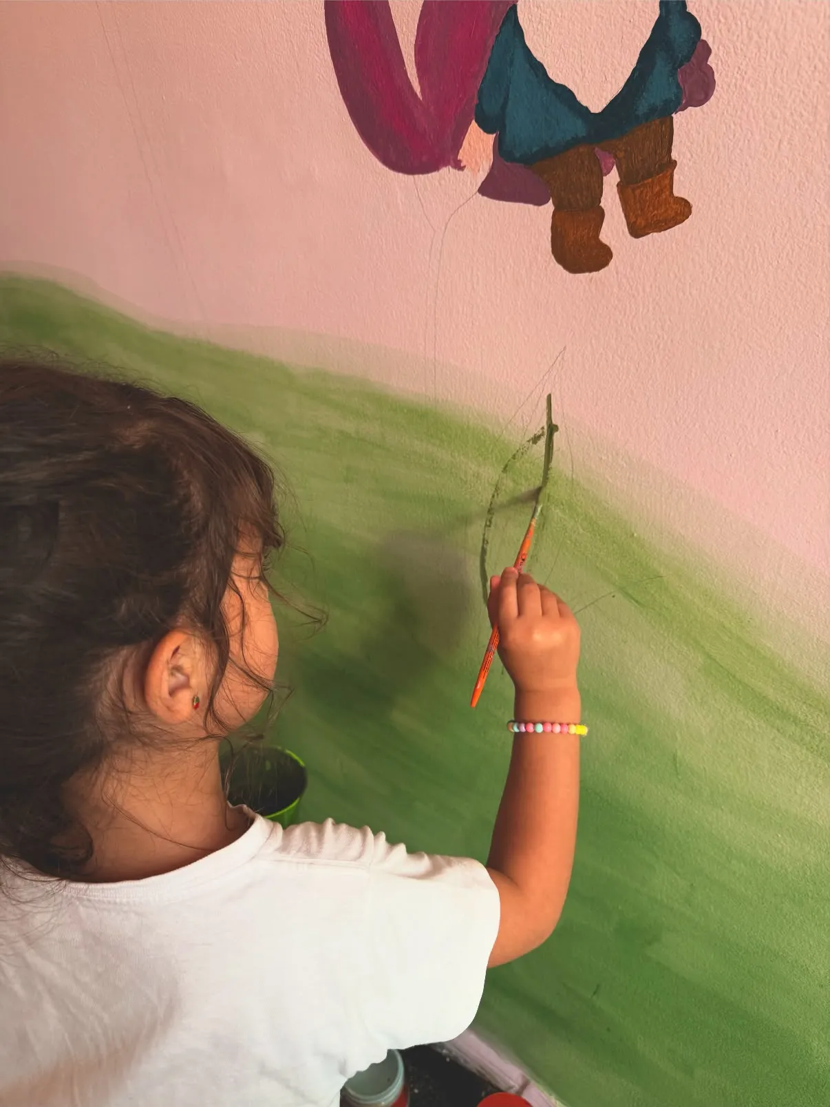 Criança pintando um mural de parede com pincel