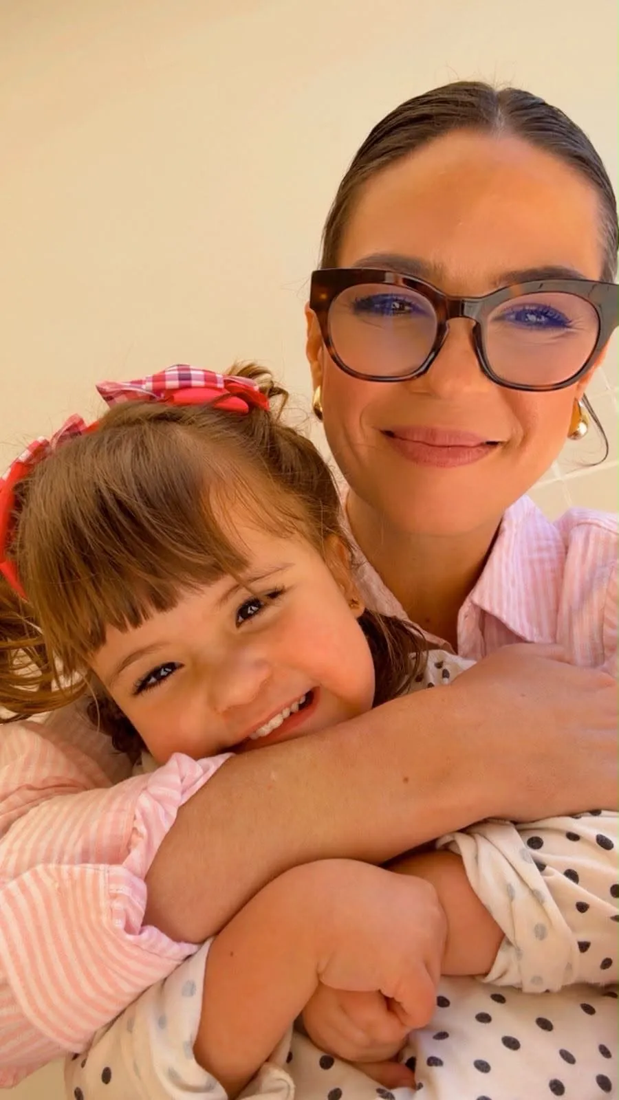 Nicole abraçando a filha, as duas sorrindo para a câmera