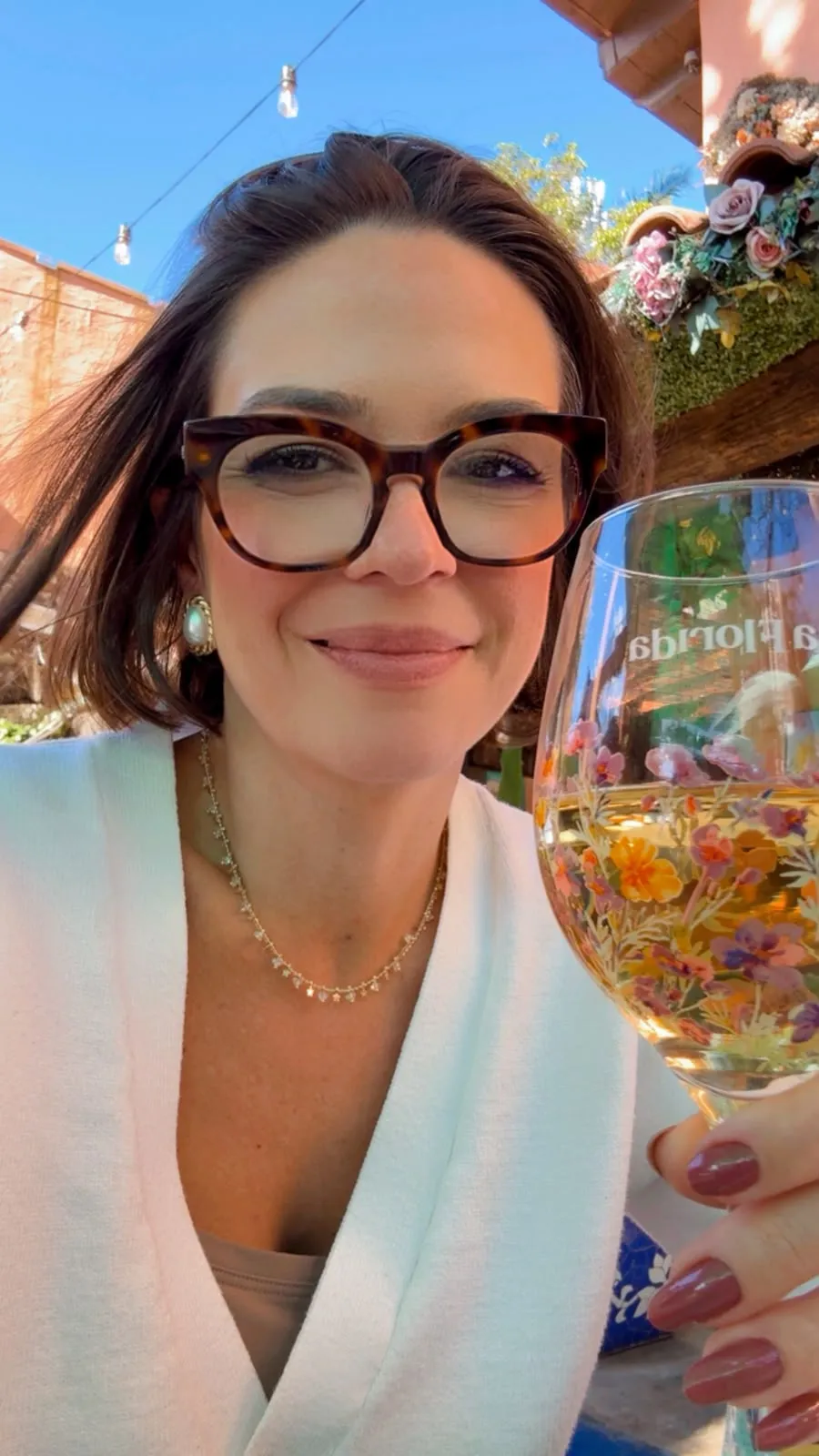 Nicole brindando com uma taça em um restaurante